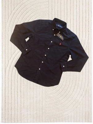 Snygg svart skjorta  - Tjena säljer nu denna stilrena Skjorta som är perfekt nu till våren och sommaren!