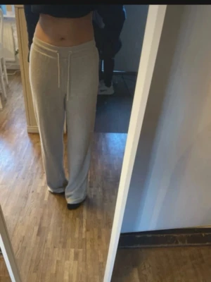 Beiga mjukisbyxor med dragsko - Säljer ett par beiga mjukisbyxor med dragsko i midjan och raka ben. Byxorna har en avslappnad passform och är perfekta för chill dagar. Materialet ser ut att vara mjukt och skönt, troligen bomull eller bomullsblandning.