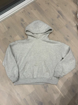 Ljusgrå hoodie från 157, storlek S - En basic ljusgrå hoodie från 157 i storlek S. Hoodien har en klassisk passform med huva, magficka och ribbade muddar vid ärmslut och midja. Perfekt för en chill och avslappnad stil. Tillverkad i mjukt och bekvämt material.