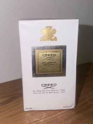 Creed Millésime Impérial Parfym 100ml - Lyxig parfym från Creed, Millésime Impérial, i elegant vit och guld förpackning. Flaskan rymmer 100 ml och har exklusiva detaljer med guldfärgad etikett och logotyp. Perfekt för dig som gillar exklusiva dofter och snygg design.