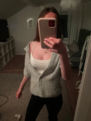 Grå ribbstickad kofta från Gina Tricot - Mysig grå kofta från Gina Tricot i ribbstickat material. Koftan har kortare ärmar och knäppning framtill med 6 kappar, i storlek S 