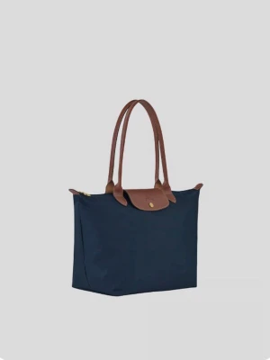 Marinblå Longchamp Le Pliage väska - Snygg marinblå handväska från Longchamp med bruna läderhandtag och lock. Väskan är tillverkad i slitstark nylon med detaljer i läder och har en klassisk, rymlig tote-modell.Storleken är M!skickar inom 1-2 dagar