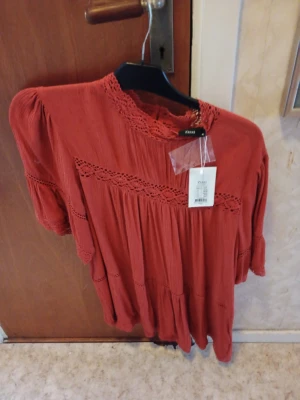 Röd blus med spets från Zizzi - Blus med spets  från Zizzi med fina spetsdetaljer och rund hals. Blusen  har korta ärmar och ett luftigt fall, perfekt för varmare dagar. Tillverkad i ett mjukt tyg som känns skönt mot huden.