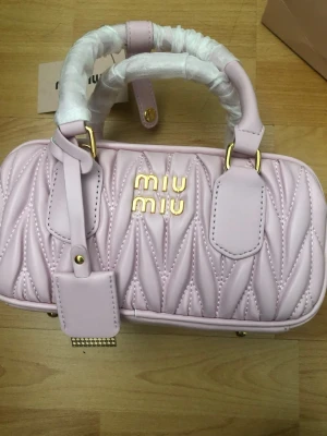Ljusrosa quiltad handväska Miu Miu - Supersnygg ljusrosa handväska från Miu Miu i quiltat läder med guldfärgade detaljer och logga framtill. Väskan har dubbla handtag, dragkedja upptill och en tag i matchande färg. Perfekt accessoar för att lyfta din outfit.