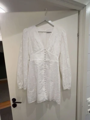 Vit kortklänning från Adoore - Säljer en vit kortklänning från Adoore med v-ringning. Använd en gång. Lite insydd i ärmarna då jag inte kände för att ha dem superpuffiga! 