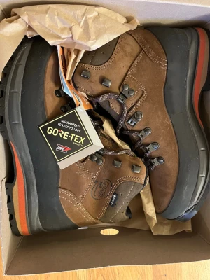 Bruna Meindl Vakuum Lady GTX kängor - Helt nya oanvända, jättesköna vandringskängor stl 41 (jag har 39 eller 40 i vanliga fall, rekommenderar att gå upp en stl och ha dubbla strumpor). Säljer ett par bruna Meindl Vakuum Lady GTX kängor i nubuckläder med Gore-Tex-membran som håller dig torr. Kraftig gummisula med orange detalj, metallhakar för snörning och robust design. Perfekta för äventyr och outdoorliv.