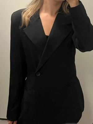 Svart kavaj Vero Moda med indragen midja - Stilren svart oversized kavaj från Vero Moda med breda slag och enkelknäppning. 