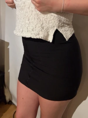 Svart tight minikjol - Säljer en svart, tight minikjol med enkel design. Kjolen har en kort passform och är perfekt att styla med crop tops eller oversized tröjor. Materialet känns mjukt och stretchigt, vilket gör den bekväm att bära hela dagen.