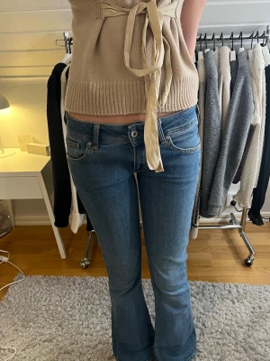 Lågmidjade bootcut jeans från Pepe jeans - Snygga blå bootcut jeans från Pepe jeans med klassisk femficksdesign och vågig brodyr på bakfickorna. Jeansen har en såå fin låg midja❤️Har lite slitningar och ett hål längst ner på baksidan men är inget man tänker på❤️❤️