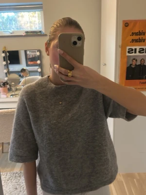 Grå kortärmad stickad tröja - Mysig grå stickad tröja med korta ärmar och rund hals. Tröjan har en avslappnad passform. Från &otherstories 
