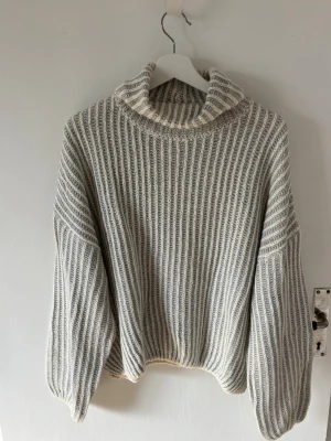 Gråvit ribbstickad polotröja - Säljer en oversized ribbstickad polotröja i gråvitt. Tröjan har breda ärmar och hög krage.Aldrig använd.