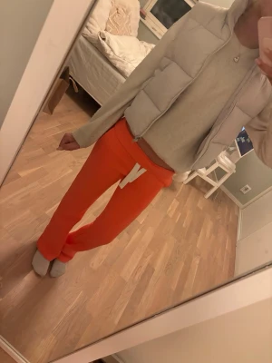 Beige dunväst med hög krage - Supersnygg beige dunväst med hög krage och dragkedja framtill. Västen har en puffig, quiltad design och två sidofickor. Perfekt att slänga över en hoodie för en chill och trendig look.