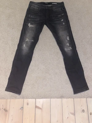 Svarta replay jeans - Säljer dessa svarta replay anbass jeans med slitningar i storlek 31/32. Använda ett fåtal gånger. Pris går att diskutera!