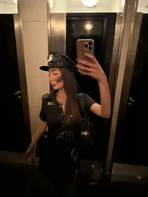 Polisdräkt med accessoarer - Snygg polisdräkt i svart med kort ärm, knappar framtill och tillhörande polishatt. Bälte med handfängsel och väska ingår. Perfekt för halloween eller någon tema fest. Allt är använt endast en kväll. Allt på bilden ingår, passar både en s och xs. 