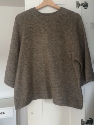 Beige stickad tröja  - Mysig beige stickad tröja med avslappnad passform. Tröjan har rund halsringning och är tillverkad i ett mjukt, melerat garn som ger en naturlig look. Perfekt för lager på lager och enkel att matcha med olika stilar.