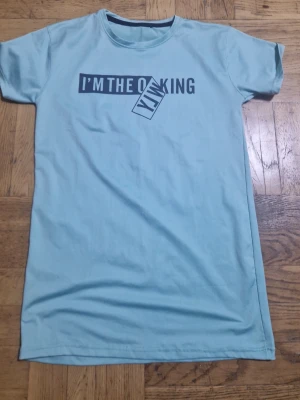 Ljusblå t-shirt med tryck - Snygg ljusblå t-shirt med texten 'I'M THE KING' tryckt framtill i svart och vitt. Klassisk rund halsringning och korta ärmar. Perfekt för en avslappnad och cool stil.