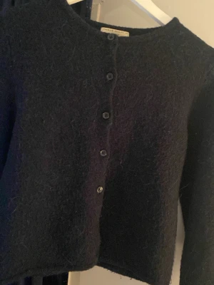 Marinblå ullkofta från Gina tricot  - Mysig marinblå kofta från Ginatricot. Rak modell med rund halsringning med knappar. Perfekt att slänga över en t-shirt eller bära som den är för en enkel men snygg look. Den är lite nopprig.