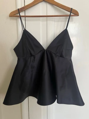 Svart satin linnetopp med smala band - Supersnygg svart linnetopp i satin med smala axelband och v-ringad front. Aldrig använd då den inte passade mig, så i helt nytt skick🥰🥰