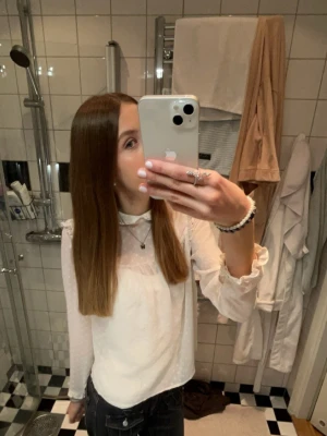 Vit blus med volang och prickar - Söt vit blus i transparent material med små prickar, volangdetaljer vid axlar och krage samt långa ärmar med resår vid ärmslut. Perfekt för en trendig och feminin look. Från hm i strl 36! 