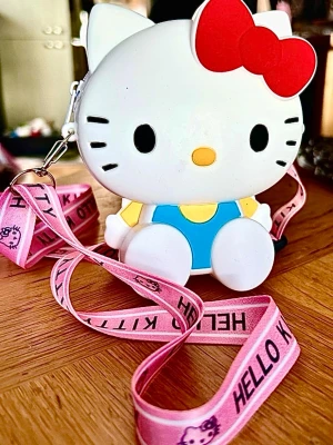 Söt liten väska med Hello Kitty-motiv! - Söt liten väska i silikon med Hello Kitty-motiv och justerbar axelrem med ett fack som stängs med dragkedja. Mått: 13 x 10 cm. Oanvänd.