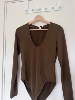 Olivgrön långärmad body - Snygg olivgrön body med långa ärmar och djup rundad urringning.