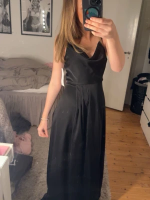 Svart långklänning med urringning  - svart långklänning med draperad urringning och smala axelband.