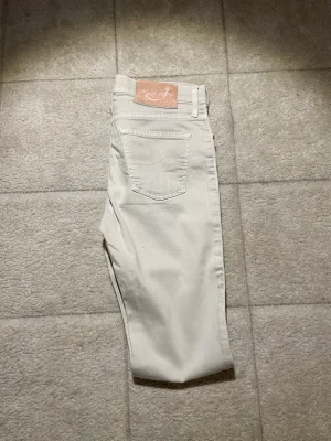 Ljusbeiga jeans från Jacob Cohen - Snygga ljusbeiga jeans från Jacob Cohen i klassisk femficksmodell. Jeansen har raka ben och är tillverkade i mjukt bomullstyg med stretch för extra komfort. Stilsäker patch med logga bak i midjan och diskreta sömmar för en clean look. 4 plagg ingår! 