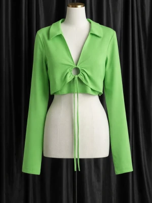 Grön croppad topp med snörning - Trendig grön croppad topp med lång ärm och krage. Toppen har en snygg ringdetalj och snörning framtill som ger en unik look. Perfekt för dig som vill sticka ut med en färgstark och modern stil.