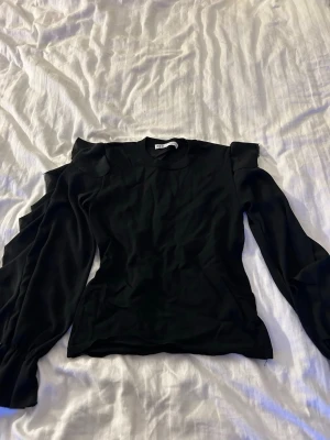 Svart topp med puffärm från Zara - Snygg svart topp från Zara med puffiga långärmar och rund halsringning. Toppens material känns mjukt och har en lätt stretch. Perfekt för dig som vill ha en trendig och stilren look med extra volym på armarna
