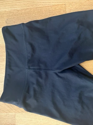 Svarta träningsshorts från H&M Move - Säljer ett par svarta träningsshorts från H&M Move med hög midja och stretchigt material. Perfekta för träning eller chill dagar. Snygg och enkel design utan synliga loggor på utsidan. Materialet är mjukt och följsamt.