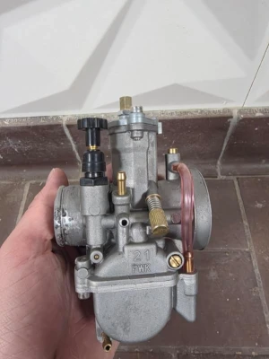 PWK 21 mm förgasare i metall - Säljer en PWK 21 mm förgasare i metall med flera justerskruvar och mässingsdetaljer. Förgasaren har en rund form och genomskinlig slang på sidan. Passar till mopeder eller mindre motorcyklar där man vill ha bättre prestanda.