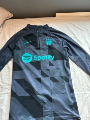 Barcelona Nike träningströja svart/blå - Snygg långärmad träningströja från Nike med FC Barcelona med svart och mörkblått geometriskt mönster.  Perfekt för fotbollsträning eller chill. Nypris 1000, andvänd 5 ggr ungefär. 