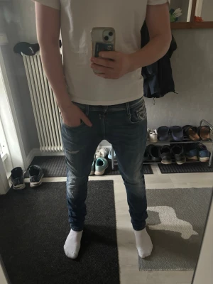Blå slim fit jeans från Replay - Säljer ett par blå slim fit jeans från Replay med slitningar och snygga tvättade detaljer. Jeansen har klassisk femficksmodell, låg midja och smal passform. Materialet är stretchigt denim som ger skön komfort och snygg look. Jag har gjort en egen slitning på jeansen det syns på bilderna, övrigt riktigt sköna och feta jeans som sitter riktigt skönt med bra stretch.