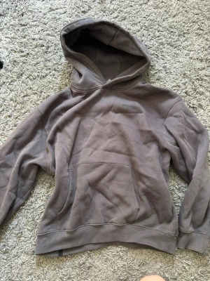 Grå hoodie från Women's Best - Säljer en grå hoodie från Women's Best med tryckt logga på bröstet. Hoodien har en stor huva och en klassisk känguruficka framtill. Den är i storlek M och knappt använd. 