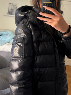 Svart Moncler Maya  - Snygg svart moncler maya. Den är i fint skick förutom några sömmar på serie lappen som lossnat. Även lite längst ner på dragkedjan har några sömmar lossnat(skriv privat för bild)💗💗
