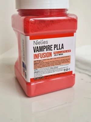 Nielies Vampire PLLA Jelly Mask - Röd jelly mask från Nielies med poly-L-lactic acid, kallad Vampire PLLA Infusion. Produkten kommer i en fyrkantig plastburk med vitt lock och är avsedd för ansiktsbehandlingar. Perfekt för dig som vill boosta huden med en innovativ mask.