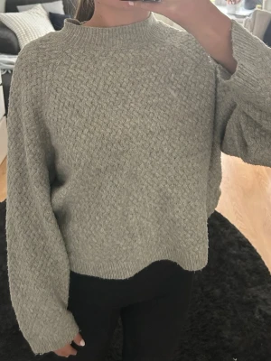 Grå stickadtröja - Mysig grå stickad tröja. Tröjan har ett snyggt strukturmönster och ribbade muddar vid hals, ärmslut och nederkant. Perfekt för kyliga dagar eller på kvällen under sommaren. 💓💓