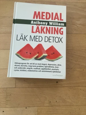 Medial Läkning: Läk med Detox - Boken 'Medial Läkning: Läk med Detox' av Anthony William är en inbunden bok med vit framsida och färgglada bilder på vattenmelon. Den innehåller hälsoprogram och tips för detox, samt riktar sig till dig som vill förbättra din hälsa genom kost och naturliga metoder.