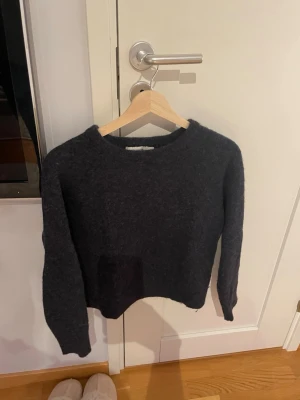 Mörkblå stickad tröja med rund hals - Mysig mörkblå stickad tröja med rund halsringning och långa ärmar. Tröjan har en enkel och stilren design, perfekt för lager-på-lager och chill dagar. Materialet ser ut att vara ullblandning för extra värme. Är storlek M men passar även en S.