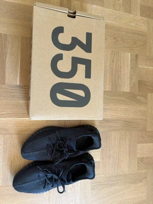 Yeezy Boost 350 V2 helsvarta sneakers - Säljer ett par helsvarta Yeezy Boost 350 V2 från Adidas. Skorna har en stickad ovandel i mesh, rundad tå och klassisk ribbad sula. Knappt använda. Skickas i originallåda.