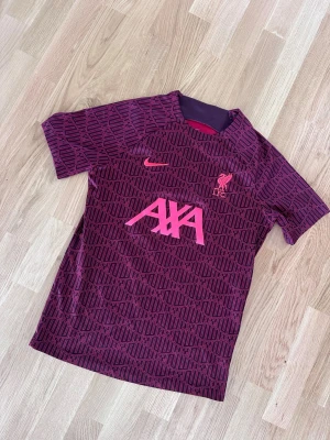 Liverpool träningströja Nike vinröd - Säljer en vinröd Liverpool FC träningströja från Nike med rosa detaljer och tryck. Fint skick