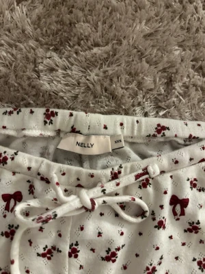 pyjamasbyxor - Supersöta vita loungewearbyxor från Nelly med röda rosetter och små blommor, i storlek xxs