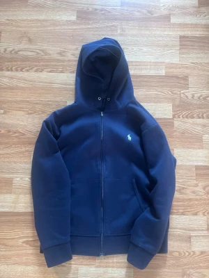 Ralph lauren hoodie (snälla köp behöver pengar för peptider) - Mörkblå hoodie med dragkedja från Polo Ralph Lauren. Klassisk design med huva, två fickor framtill och vit broderad logga på bröstet. Perfekt för en avslappnad och stilren look.