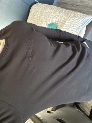 Svart sweatshirt från Pelle Petterson  - Svart sweatshirt från Pelle Petterson  med broderad logga på bröstet. Tröjan har rund halsringning, långa ärmar och ribbade muddar vid ärmslut och nederkant. Tillverkad i mjukt bomullsmaterial för en bekväm och stilren look.
