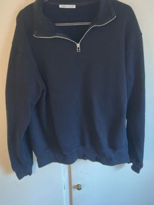 Svart halvzip hoodie från Zara - En svart hoodie från Zara med halv dragkedja framtill och hög krage. Tröjan har en avslappnad passform och är tillverkad i mjukt sweatshirtmaterial. Perfekt för en chill och stilren look.