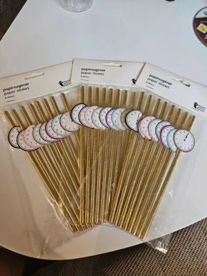 Guldfärgade papperssugrör med klockmotiv - Säljer tre paket guldfärgade papperssugrör från Flying Tiger Copenhagen. Varje sugrör har en pappersdekoration i form av en klocka i olika färger. Perfekt till fest eller nyårsfirande. Varje paket innehåller 8 sugrör.  Kan även hämtas I Partille