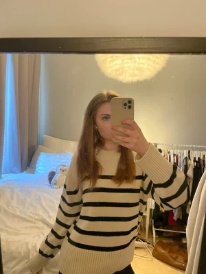 Beige stickad tröja med svarta ränder - Säljer en beige stickad tröja med svarta horisontella ränder. Tröjan har en avslappnad passform, rund halsringning och ribbade muddar vid ärmslut och nederkant. Perfekt för dig som gillar klassisk och enkel stil.