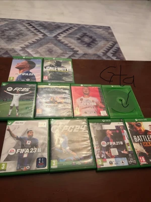 Xbox One spelpaket med FIFA, COD & fler - Samling med Xbox One-spel: FIFA 22, FIFA 23, FIFA 21, FIFA 20, FIFA 25, EA Sports FC 24, Call of Duty, Battlefield Hardline, Destiny och ett GTA. Alla fodral är gröna och spelen är original. Perfekt för dig som gillar sport, action och äventyr.