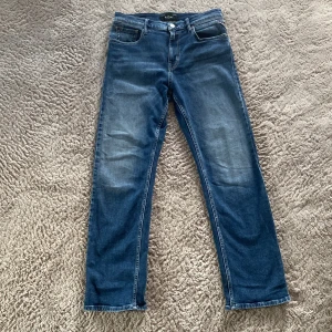 Blåa jeans från Replay, rak modell - Säljer ett par klassiska blå jeans från Replay i rak passform. Nästan aldrig använda. Jeansen har fem fickor, snygga slitningar och Replay-logga på fickan. Perfekta för dig som gillar en tidlös look och vill ha ett par jeans som funkar till allt. Pris kan diskuteras!