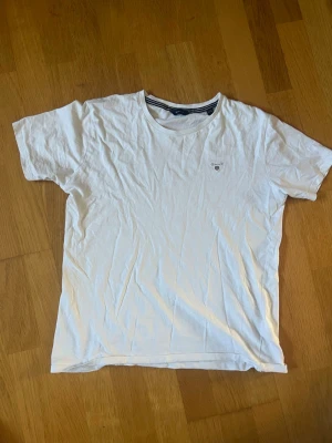 Vit t-shirt från Gant - Klassisk vit t-shirt från Gant med rund halsringning och diskret logga på bröstet. Tillverkad i mjuk bomull och har en normal passform med korta ärmar. Perfekt basplagg för alla tillfällen. 